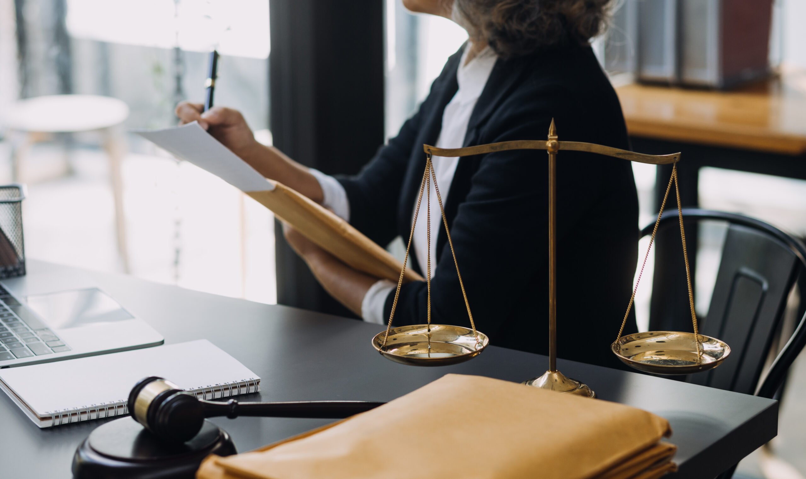 law books and scales of justice on desk in library of law firm. law books and scales of justice on desk in library of law firm.