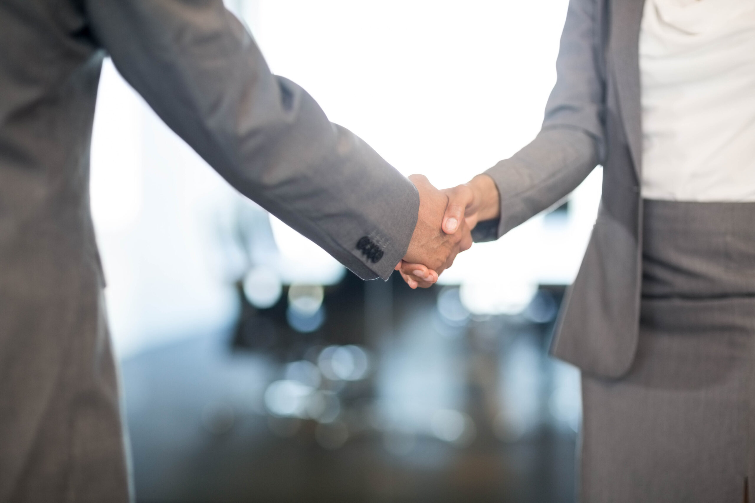 Close-up of businessman shaking hands with businesswoman in office Close-up of businessman shaking hands with businesswoman in office